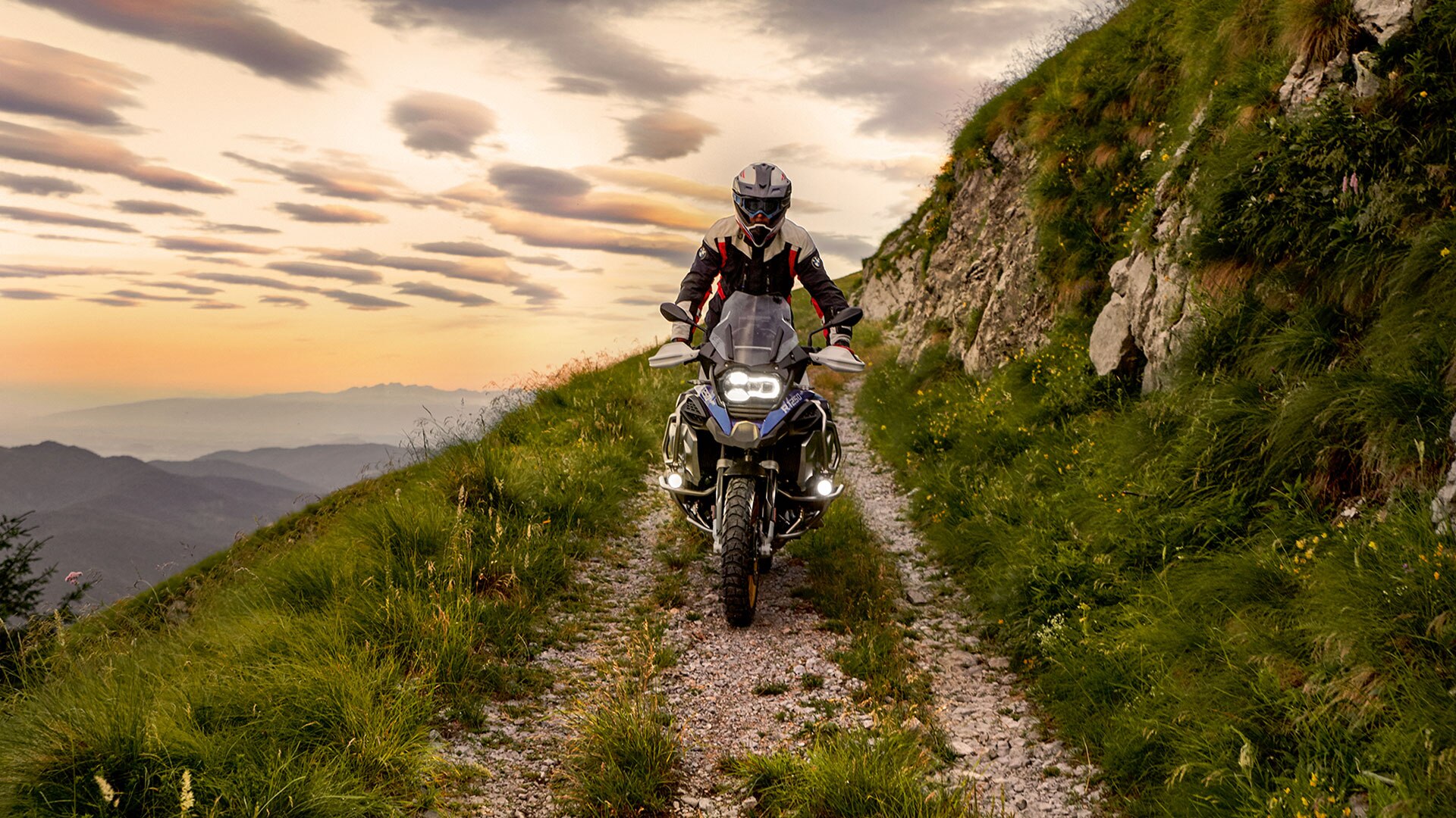 Escena de conducción con la BMW R 1250 GS Adventure en las montañas en un camino no asfaltado