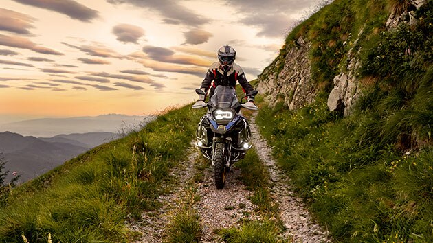 Escena de conducción con la BMW R 1250 GS Adventure en las montañas en un camino no asfaltado