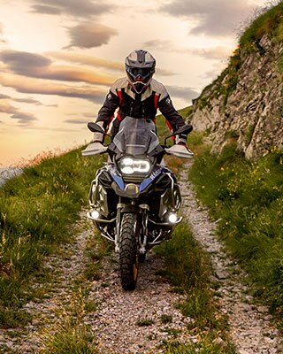 Escena de conducción con la BMW R 1250 GS Adventure en las montañas en un camino no asfaltado